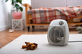 Fan heater on the floor in living room with sofa at background