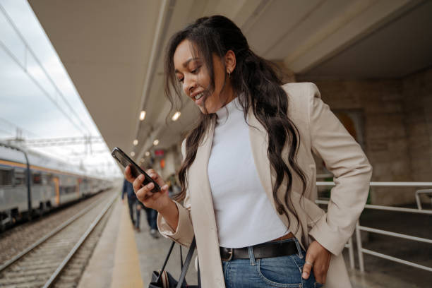 istock Mixed race woman using mobile phone communication online standing at railway station 1690938467