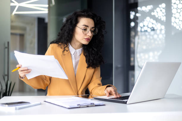 istock Serious focused female financier working inside office with documents and papers at workplace, hispanic woman thinking about bills on paper work 1690943771