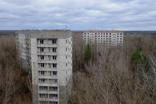 Abandoned panel houses among leafless trees in Pripyat. Beautiful cloudy sky over the city. Post-Soviet architecture.