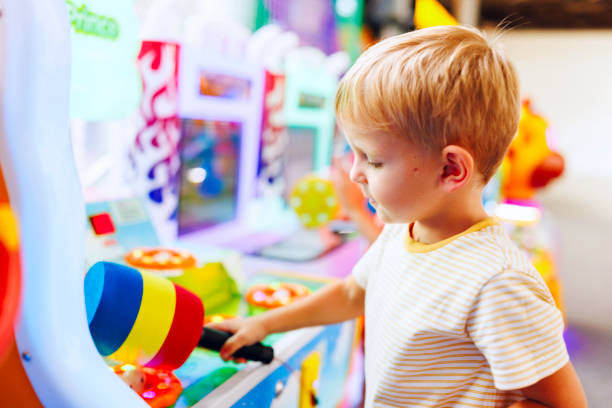 istock Happy little boy playing fun games on arcade machine at an amusement park 1690956969
