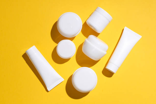 istock White cream jars and tubes on yellow background with shadow. Creative beauty layout. Top view. 1690958317