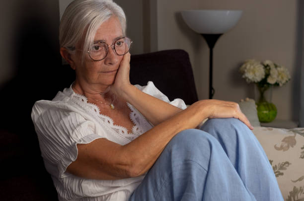 istock Lonely melancholic elderly woman sitting on sofa with hand on face while looking into space, thoughtful elderly lady with health or family problems 1690958444