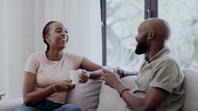 Black couple, drinking coffee and conversation at home on a living room sofa with love and care. Tea, talking and bonding with marriage on a sofa with discussion, funny joke and laughing in morning