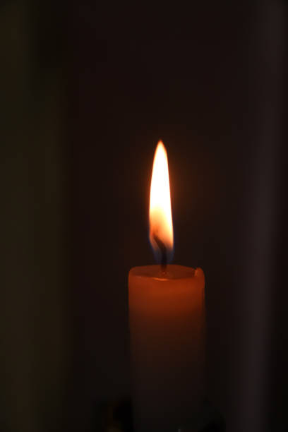 istock Defocus close up single candle light and flame on black background. Vertical. RIP flame. Memory. Out of focus 1690961611