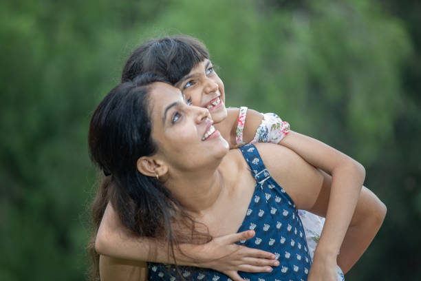 istock Mother piggybacking smiling daughter in park 1690961728