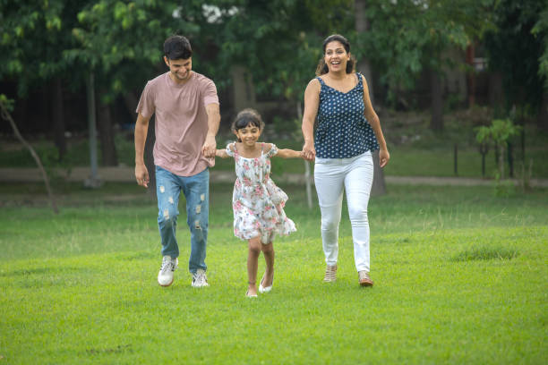 istock Parents and daughter holding hands and running in park 1690961816