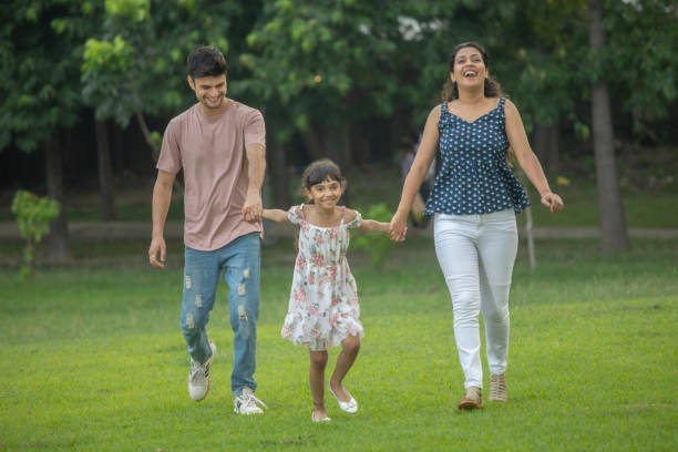 istock Parents and daughter holding hands and running in park 1690961854