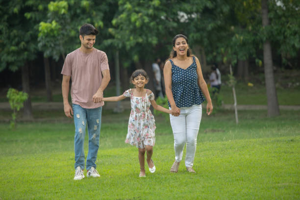 istock Parents and daughter holding hands and walking in park 1690961899