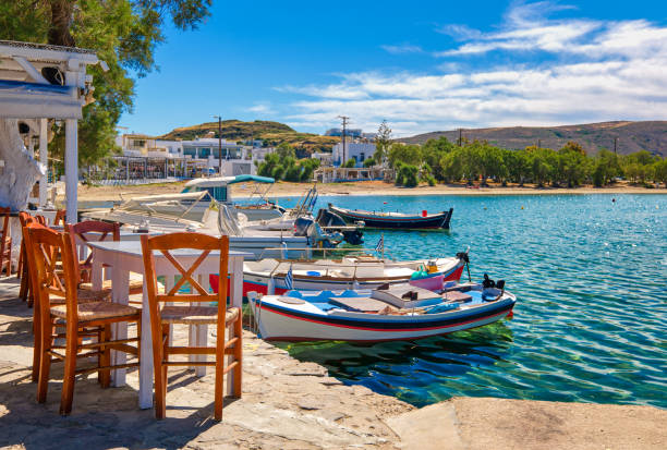 colorful chairs and tables of greek tavern by waterfront at day. vacations, greece, summer, restaurant, outdoor dining, islands, port, marina, yachts - dining nautical vessel recreational boat europe imagens e fotografias de stock