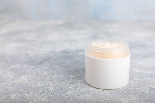 istock Body and hand cream with chamomile extract on  background. Herbal dermatological cosmetic hygiene cream. Natural beauty product. Cosmetic cream with flowers on wooden background. Spa concept. 1690967222