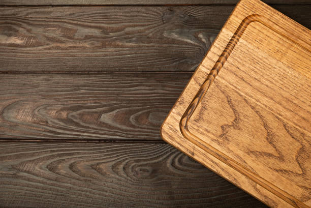 istock Cutting board over towel on wooden kitchen table. Cutting board and kitchen towel on black textured background. Menu food card or recipes background concept.MOCKUP. Design. Place for text, copy space. 1690983367