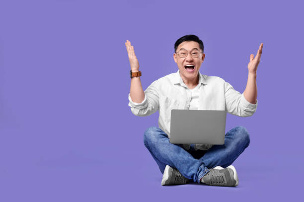 istock Emotional man with laptop on lilac background, space for text 1690992141
