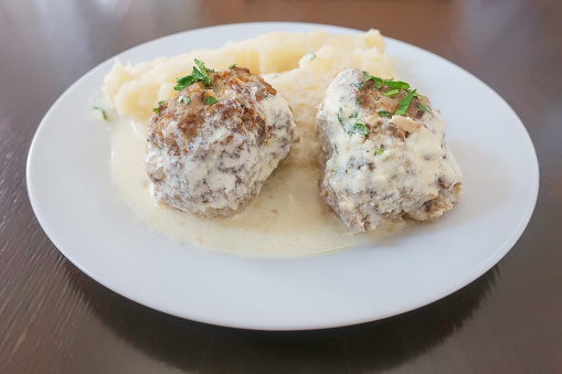 Two meat cutlets with mashed potatoes, poured with sauce on a white plate plate