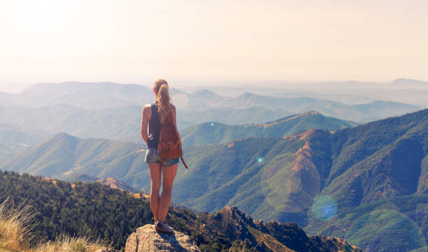 istock Woman standing on rock looking mountains range landscape 1691001897
