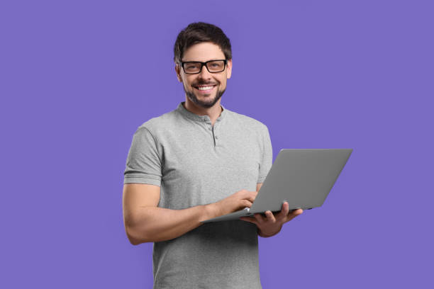 istock Happy man with laptop on lilac background 1691001926