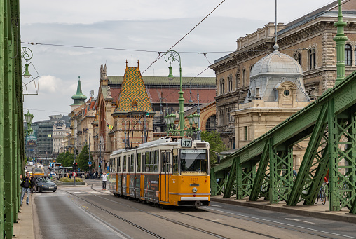 Budapest, Hungary - April 24, 2023: A picture of the Liberty Bridge and a yellow tram passing through it, in Budapest.