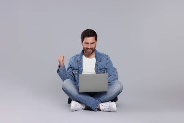 istock Emotional man with laptop on light grey background 1691014602