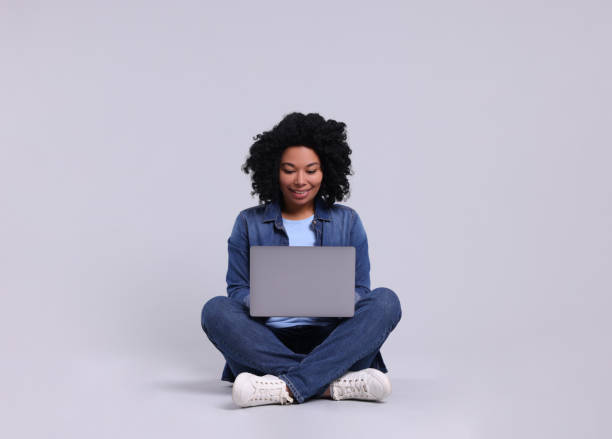 istock Happy young woman with laptop on light grey background 1691016567