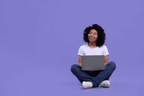 istock Happy young woman using laptop on purple background. Space for text 1691017095