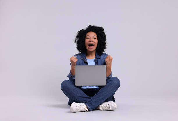 istock Emotional young woman with laptop on light grey background 1691017111