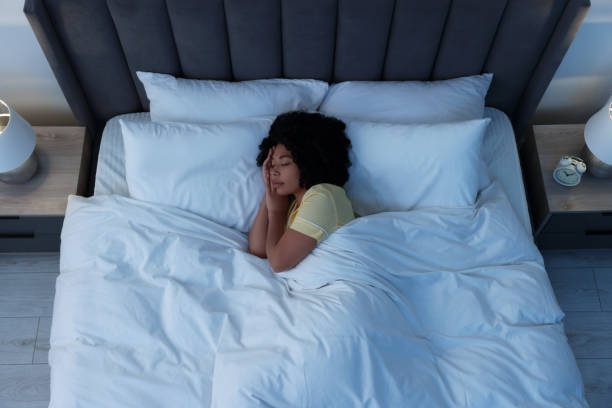 istock Young woman sleeping in soft bed at night, above view 1691017162