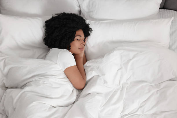 istock Beautiful young woman sleeping in soft bed, top view 1691017680