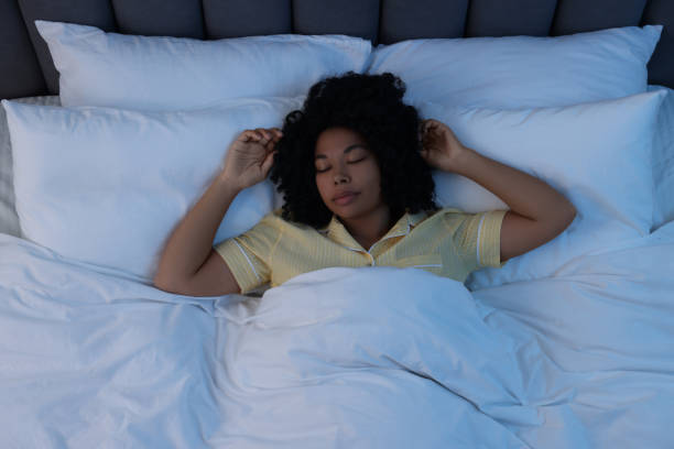 istock Young woman sleeping in soft bed at night, above view 1691018311