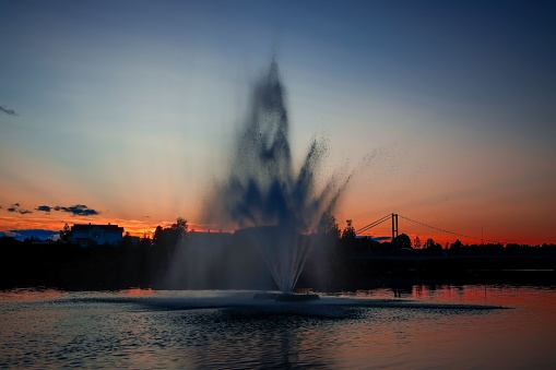 A vibrant skyline with a majestic water fountain illuminated by a golden sunset, creating a breathtaking scene