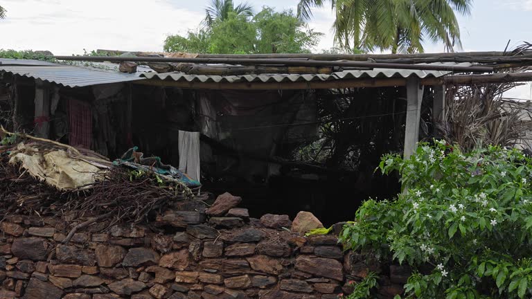 A wide view of an old stone barn with a cowshed in a rural village during rain