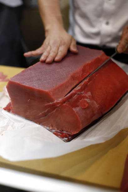 нарезка красной корейки тунца кухонным ножом - tuna tuna steak raw bluefin tuna стоковые фото и изображения
