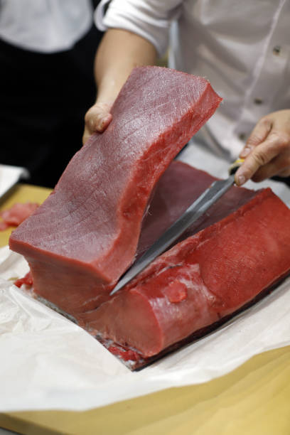 шеф-повар разделывает корейку тунца кухонным ножом - tuna tuna steak raw bluefin tuna стоковые фото и изображения
