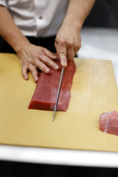 шеф-повар разделывает тунца кухонным ножом для приготовления суши - tuna tuna steak raw bluefin tuna стоковые фото и изображения