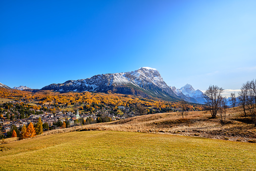 The larch forests with the orange autumn colors surround the city of Cortina D'Ampezzo. In the background the Sorapis massif in the Belluno Dolomites, Veneto, Italy, Europe, a popular destination for climbing, walking, trekking, skiing, snowshoeing, hiking.
