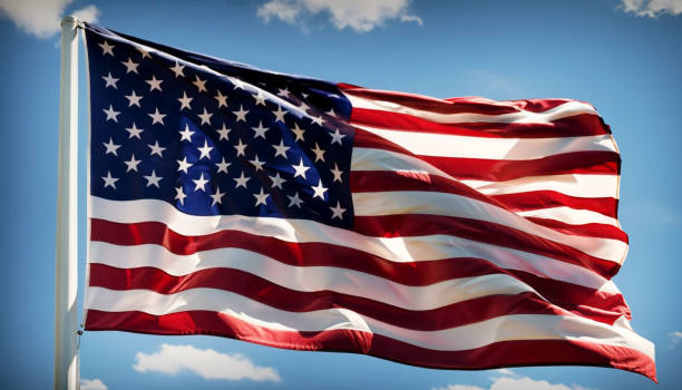 istock Large American Flag on Flagpole Blowing in the Wind with Blue Sky 1691066809