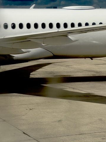 Detail of commercial airplane row of windows while the shadow of the wings shows up in the runway