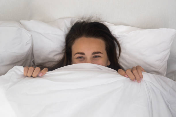 istock joyful woman, smiling from blanket, concealing face while luxuriating in bed on a bright morning 1691079977