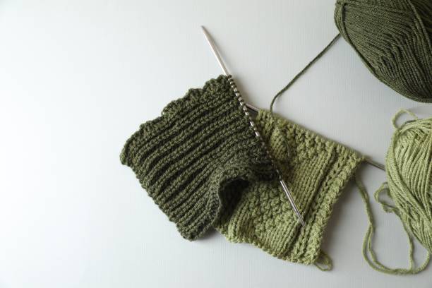 istock Green knitting, needles and soft yarns on light background, flat lay. Space for text 1691087847