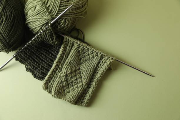 istock Knitting, needles and soft yarns on light green background, above view. Space for text 1691088405