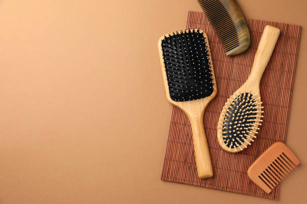istock Wooden hairbrushes and combs on light brown background, flat lay. Space for text 1691088950