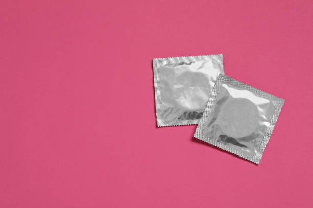 paquetes de condones sobre fondo rosa, planos y espacio para texto. sexo seguro - condom sex sexually transmitted disease aids fotografías e imágenes de stock