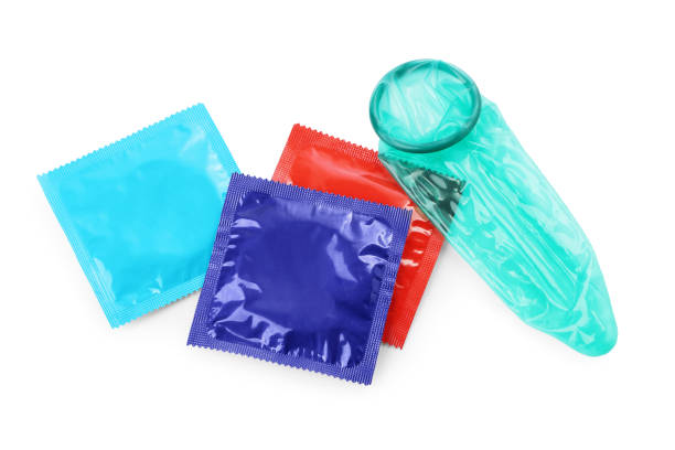 condón desenrollado y paquetes sobre fondo blanco, vista superior. sexo seguro - condom sex sexually transmitted disease aids fotografías e imágenes de stock