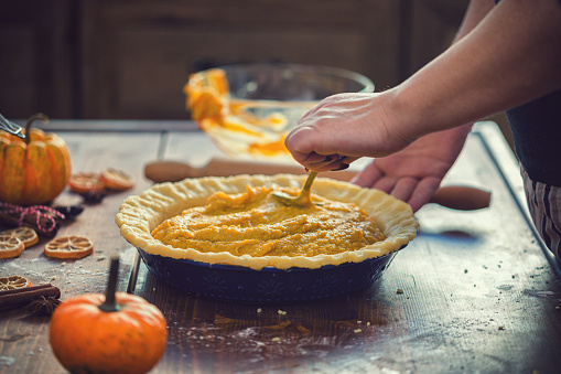 Woman preparing  pumpkin pie for the holidays at home