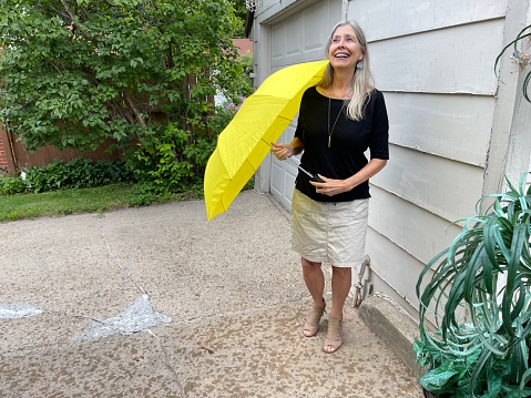 Happy senior woman holds an open red umbrella outdoors