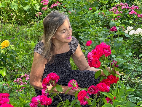 Beautiful woman in the country with a bush of beautiful roses.