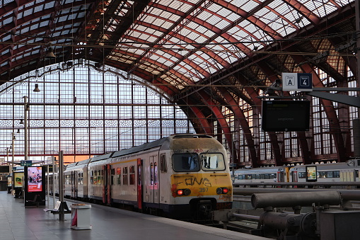 A picture taken of a train waiting for its passengers to board, on the top floor of the central station of antwerp, underneath the famous metal and glass dome.