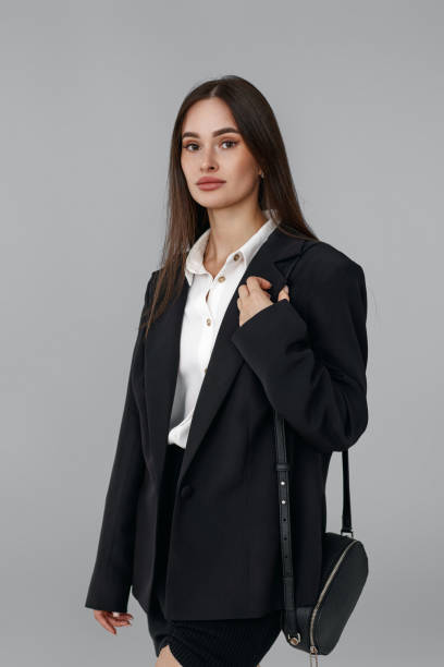 woman with handbag in black blazer isolated on grey background