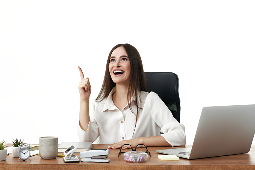 happy businesswoman using laptop and pointing up on white background