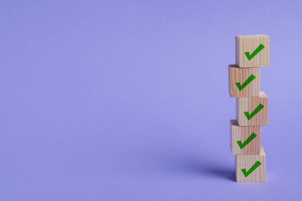 istock Stacked wooden cubes with check marks on light violet background. Space for text 1691134169
