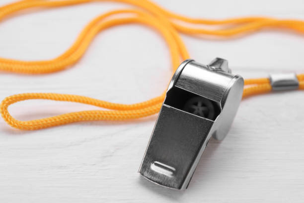 istock One metal whistle with cord on white wooden table, closeup 1691136363